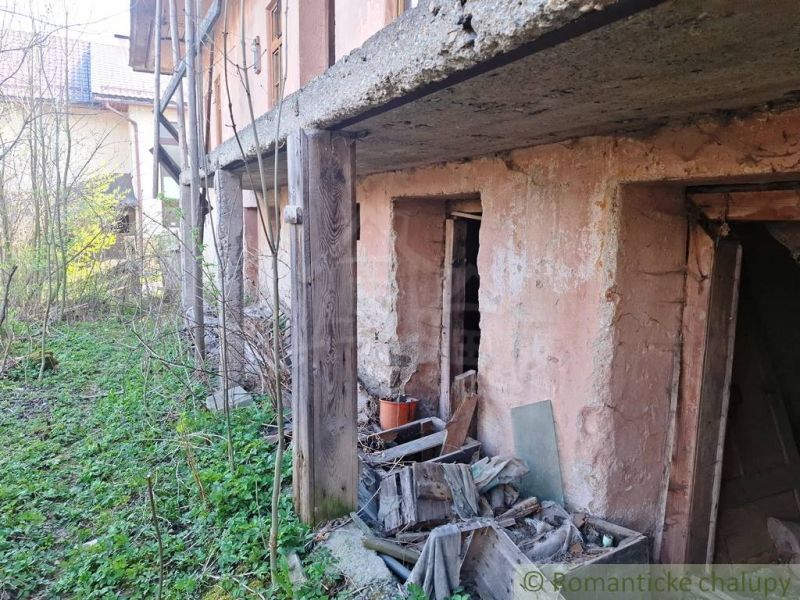 An abandoned building among peculiar properties in Heľpa with a damaged facade and an unkempt garden.