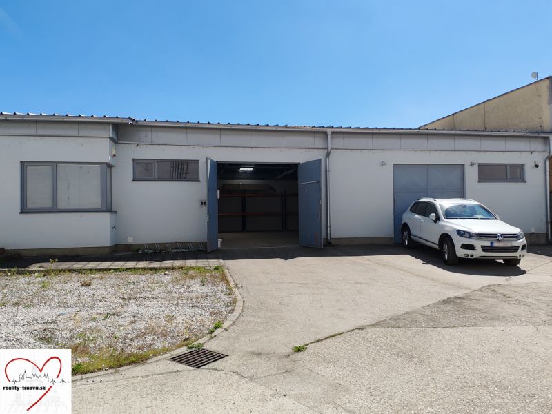 A white warehouse and hall building in Trnava with a car in the parking lot.