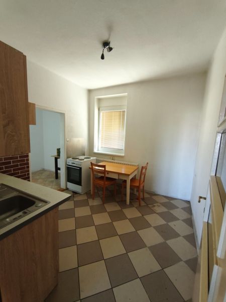 A kitchen in a family house with a white stove, a table, and orange chairs.