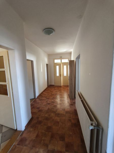 A narrow hallway with a tiled floor and light-colored walls in a family house.