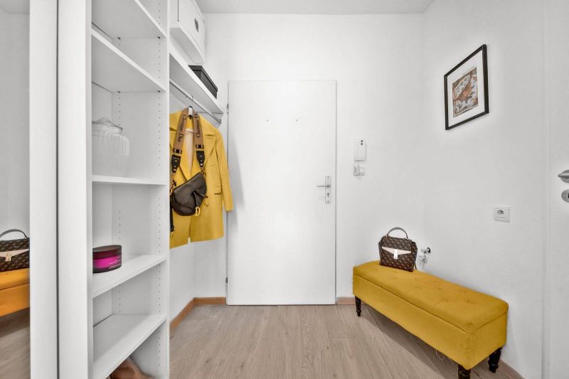 Entrance hall in a 2-room apartment with storage shelves and wood-patterned flooring.