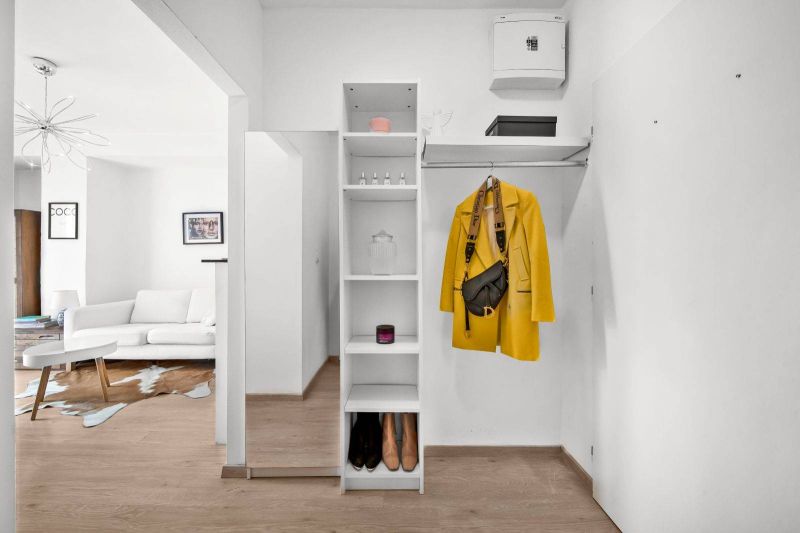Hallway of a 2-room apartment with a shelf, mirror, and floor with a wood decor.