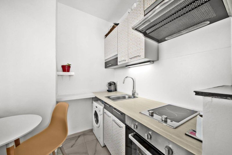 A kitchen in a 2-room apartment with a dishwasher, washing machine, and coffee maker.