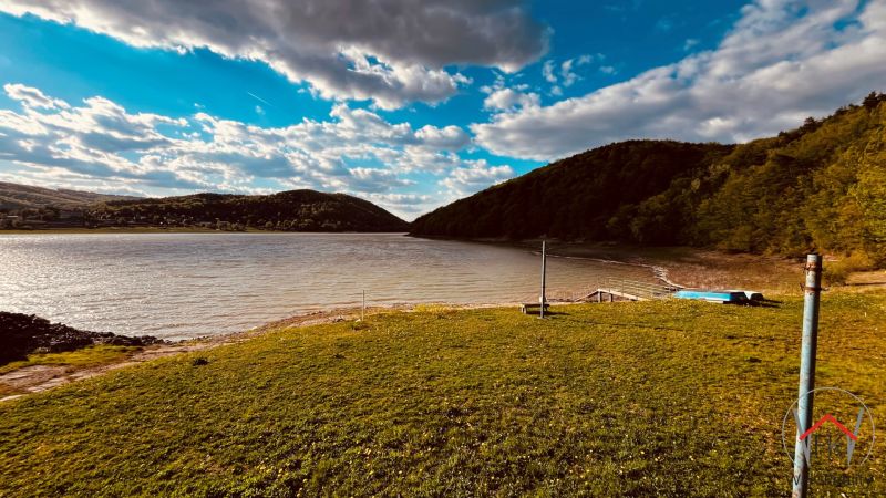 A lake with a sky and hills in the area of Nova Kelca near the recreational cottage zone.