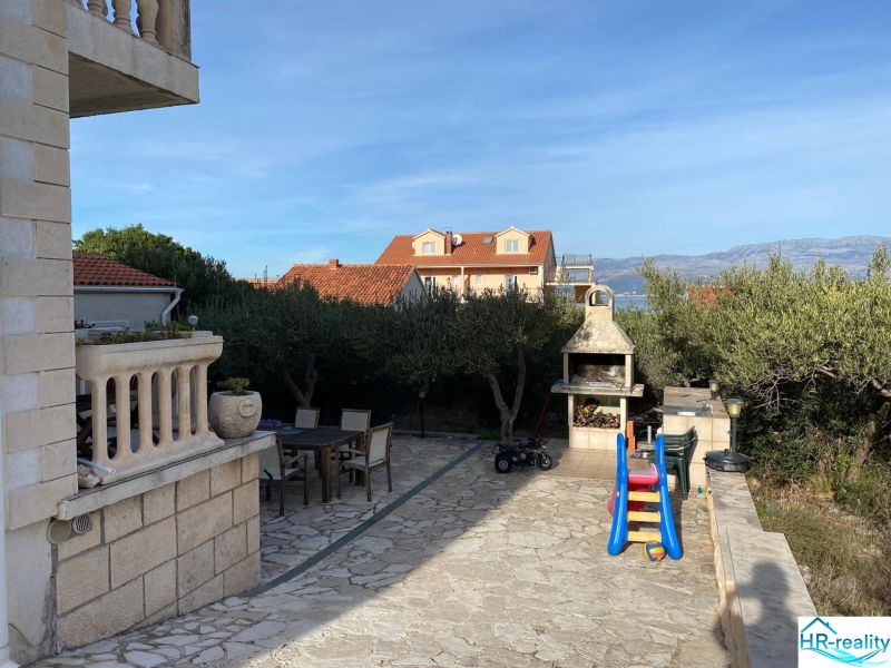 Exterior of a holiday apartment on Brač with a terrace, barbecue, and children's slide.