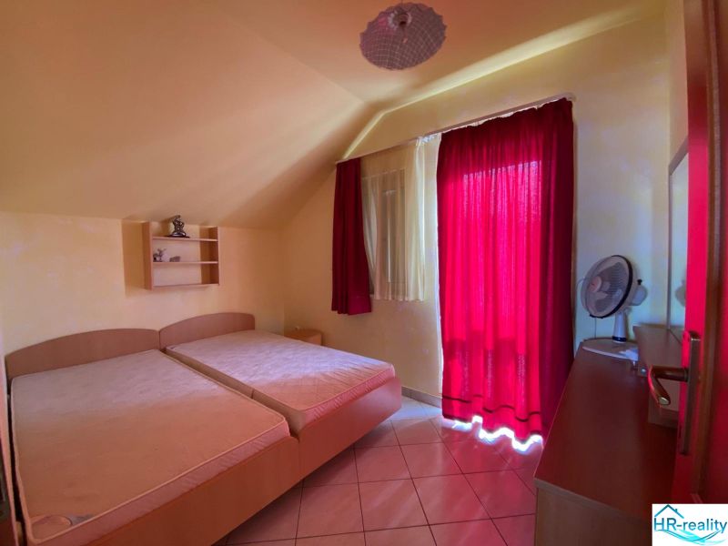 Bedroom in a Holiday Apartment with two beds, a red curtain, and a shelf.