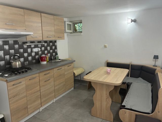 A kitchen in a cottage with a stove, wooden cabinets, and a corner bench.
