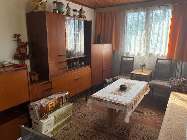 Living room in a cottage with rustic furniture, carpet, and wooden decor flooring.
