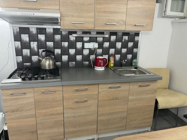 A kitchen unit in a cottage with a sink, gas stove, and marble decor tiles.