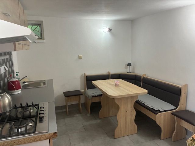A kitchen in a cottage with a corner bench, table, and cooktop.