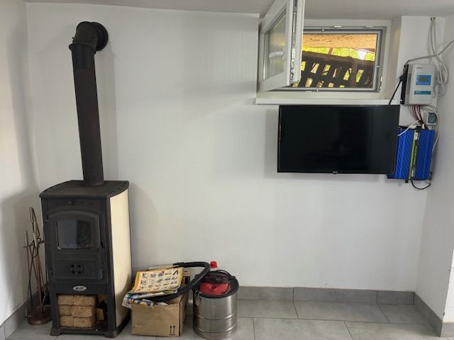 A cottage with tiles, a television, and a supply of wood on a tiled floor.