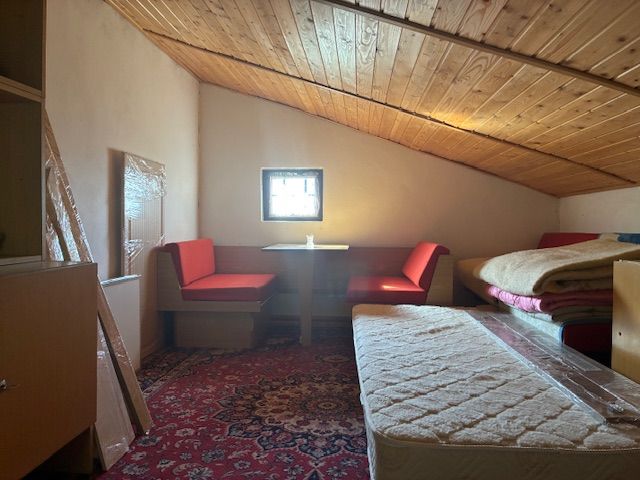 Attic room in a cottage with a wooden ceiling and seating on a red carpet.