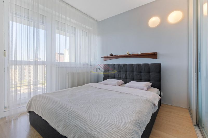 Bedroom in a 2-room apartment with a large bed, curtains, and a floor with a wood decor.