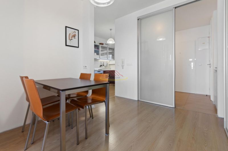 Dining area with brown chairs, wooden decor flooring in a 2-room apartment.