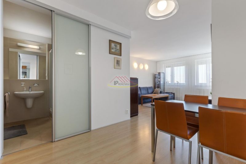 Dining area and living room in a two-room apartment with wood-patterned flooring.