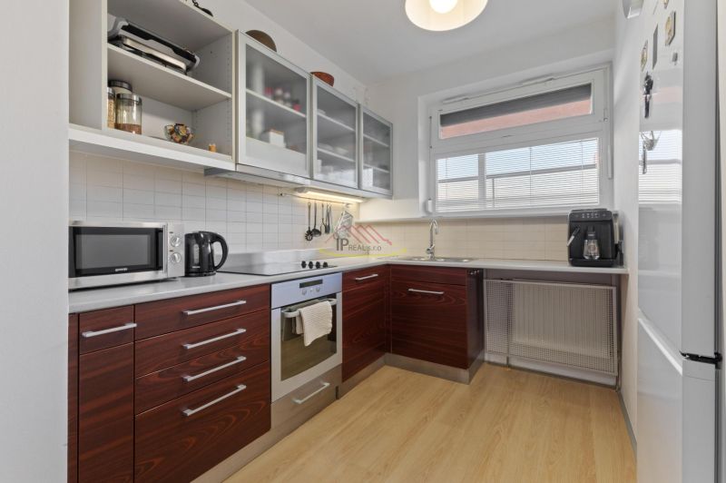A kitchen in a 2-room apartment with a kitchenette and appliances, flooring with a wood decor.