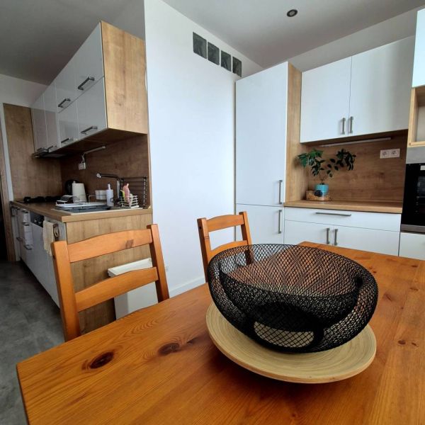 A kitchen in a 3-room apartment with wooden decor and white cabinets.