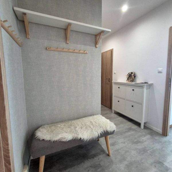 The hallway of a 3-room apartment with a bench, a coat rack, and a shoe cabinet.