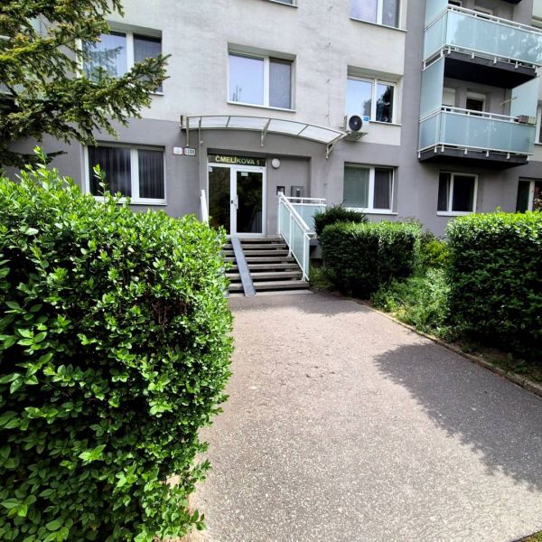 The entrance to the apartment building on Čmelíkova Street in Bratislava - Ružinov surrounded by greenery.