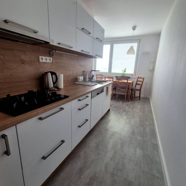 A kitchen in a 3-room apartment with a dining table and a wooden decor floor.