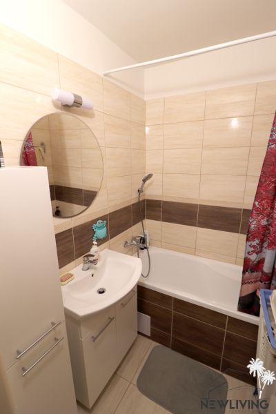 Bathroom in a 2-room apartment with a mirror, sink, and bathtub.