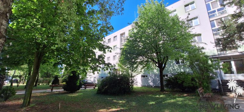 An apartment building on Vrbovská Street in Piešťany surrounded by greenery with benches for seating.