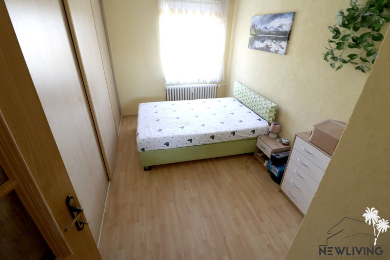 Bedroom with a double bed, wardrobe, and wooden decor flooring in a 2-room apartment.