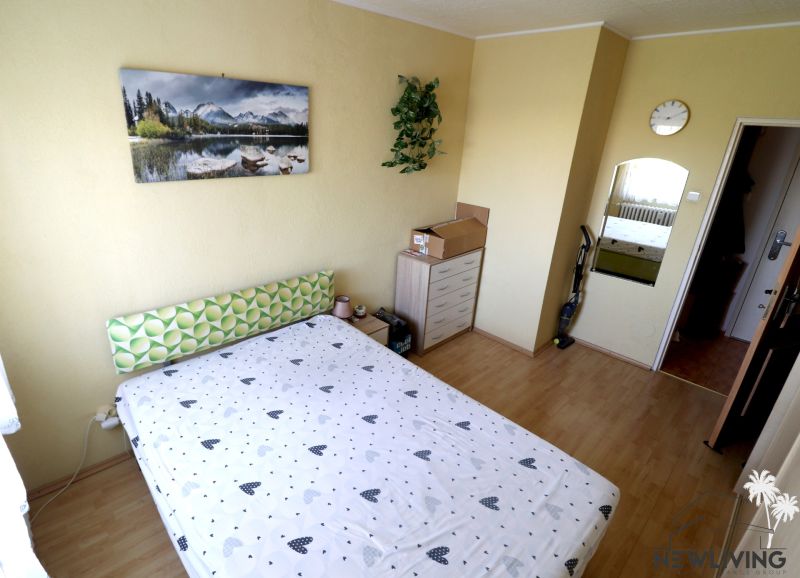 A bedroom with a mirror, a dresser, and a wooden decor floor in a two-room apartment.