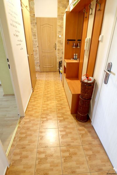 A hallway in a 2-room apartment with tiles and wall hooks.