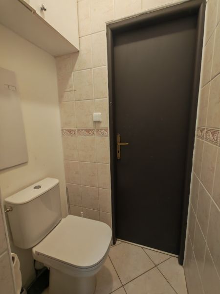 A toilet in a 3-room apartment with light tiles and a white toilet.