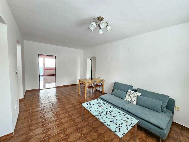 Living room of a 3-room apartment with a sofa, coffee table, and dining table.