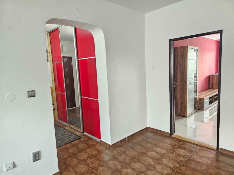 A hallway in a 3-room apartment with red cabinets and a brown floor.