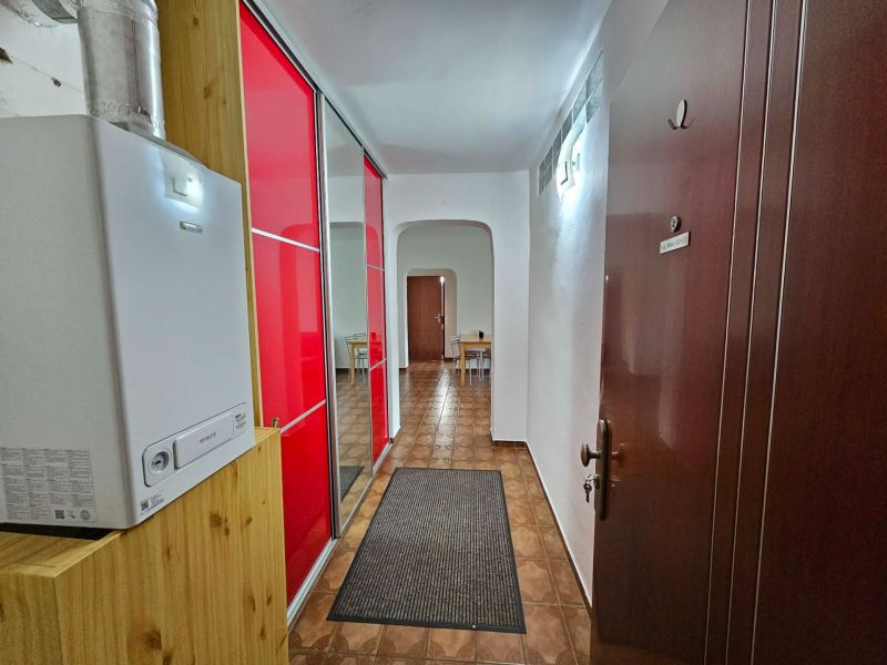 A hallway in a 3-room apartment with a red wardrobe and a gas boiler.