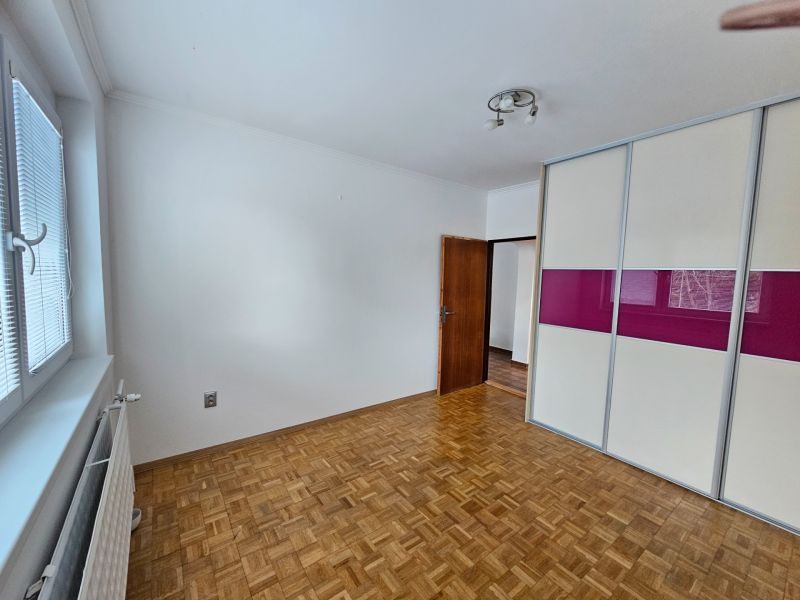 A room with a wooden floor design, a built-in wardrobe, and a large window, 3-room apartment.