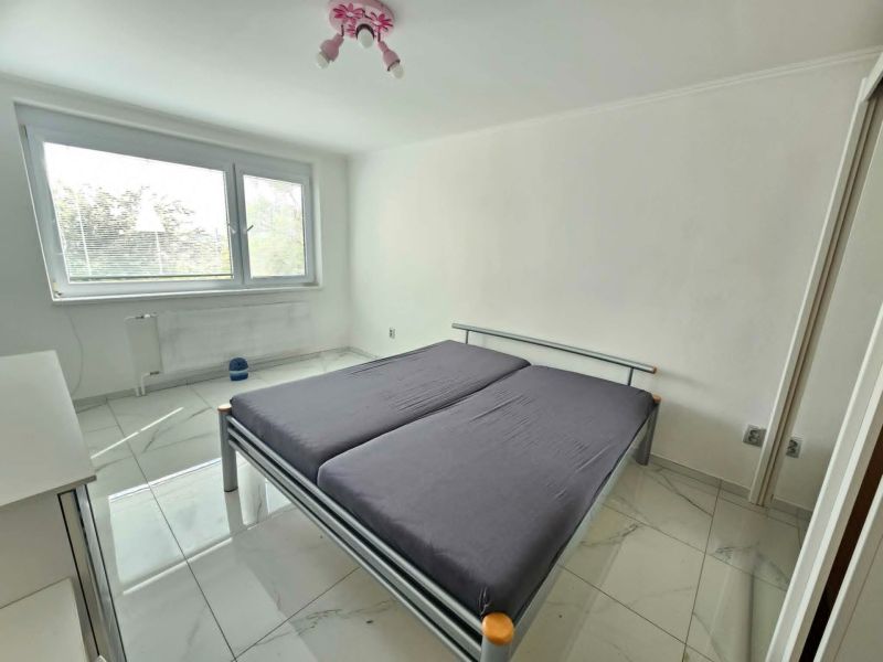 Bedroom with a large bed and white walls in a 3-room apartment, light ceramic floor.