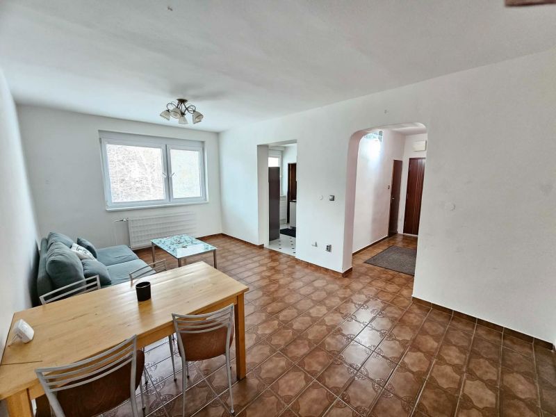 Living room in a 3-room apartment with a brown floor and simple seating.