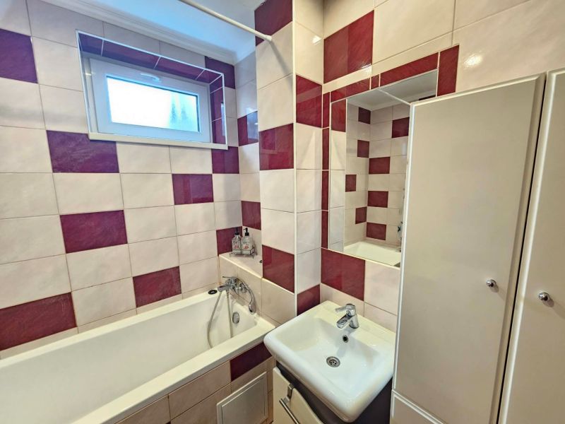 A bathroom in a three-room apartment with square tiles and a bathtub.