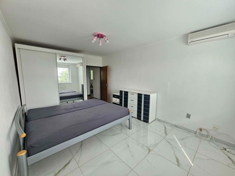 A bedroom with a tiled floor, a bed, and a built-in wardrobe in a 3-room apartment.