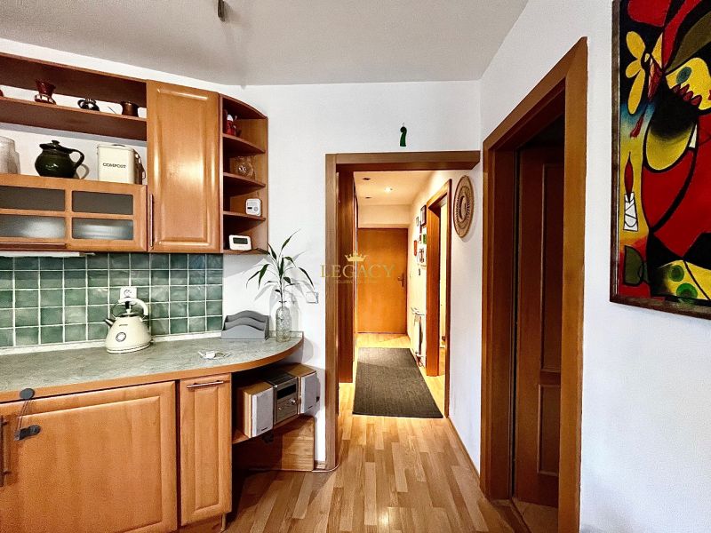 A kitchen in a 3-room apartment with a wooden decor floor and green tiles.