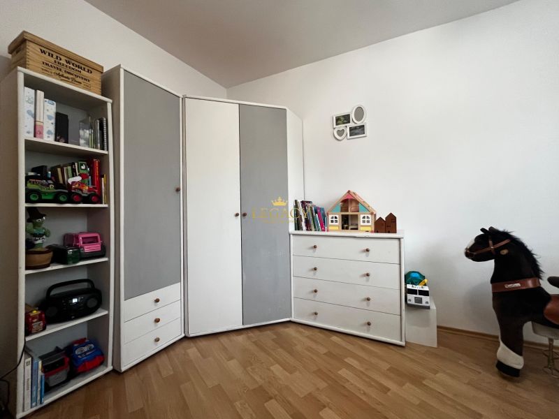 Children's room in a 3-room apartment with a wooden decor floor, toys, and white furniture.