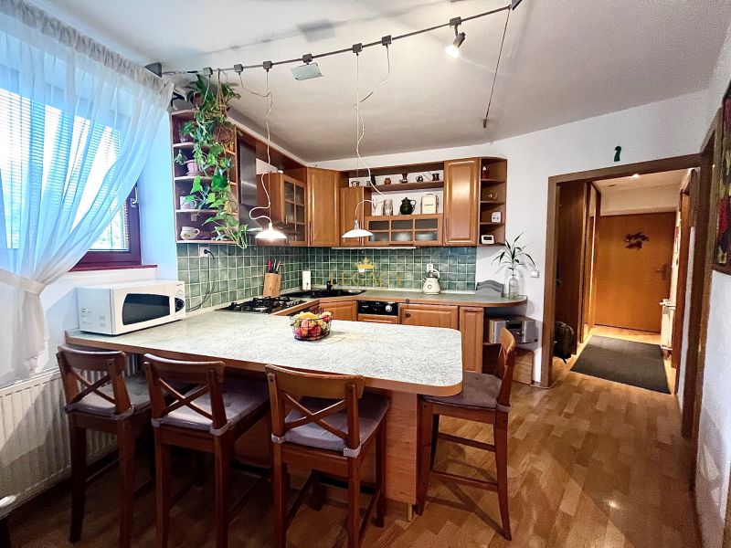 The kitchen of a 3-room apartment with a wooden decor floor and green glass mosaic.