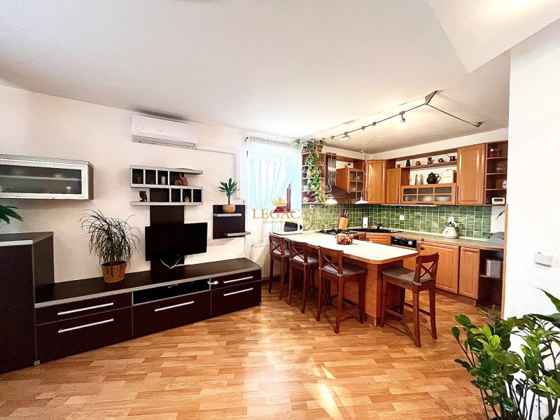 A kitchen in a 3-room apartment with an island, wooden decor flooring, and an open space.