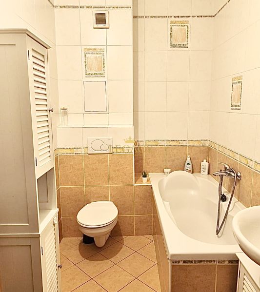 Bathroom with a bathtub and toilet in a 3-room apartment with white tiles.