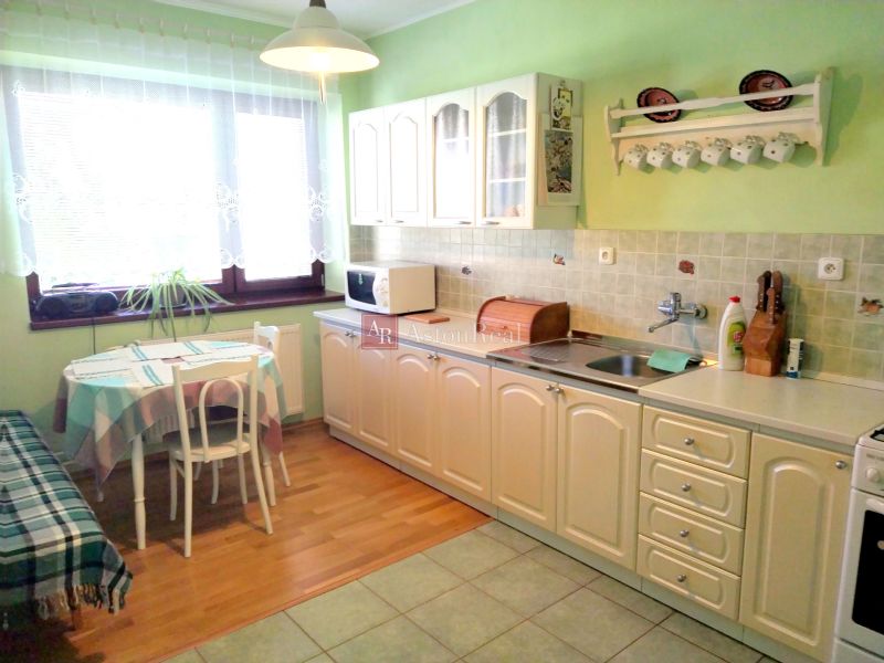 A kitchen with a dining table and a wooden decor floor in a family house.