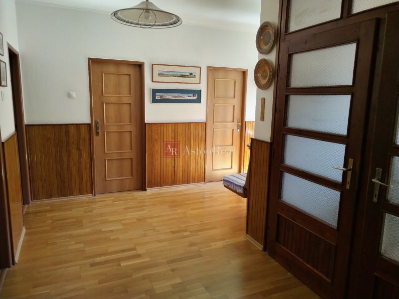 A hallway in a family house with walls of wooden decor and a floor with wooden decor.