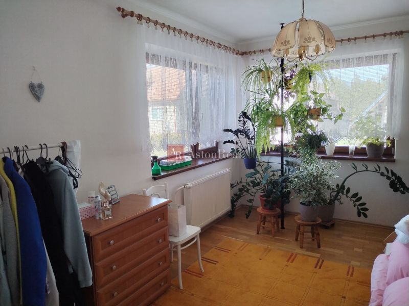 A room in a family house with lots of plants and furniture, a floor with a wooden decor.