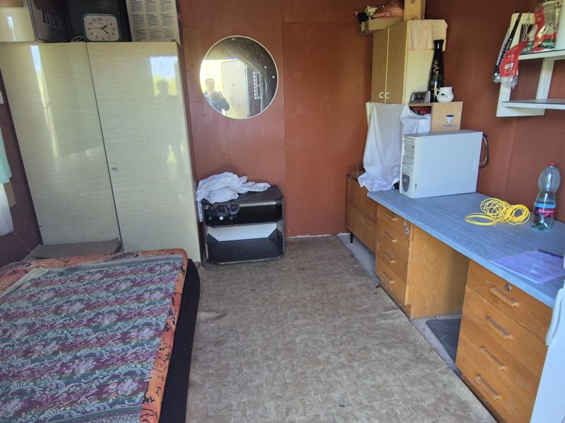 A room in the garden with older furniture, a mirror, and a table with a computer.