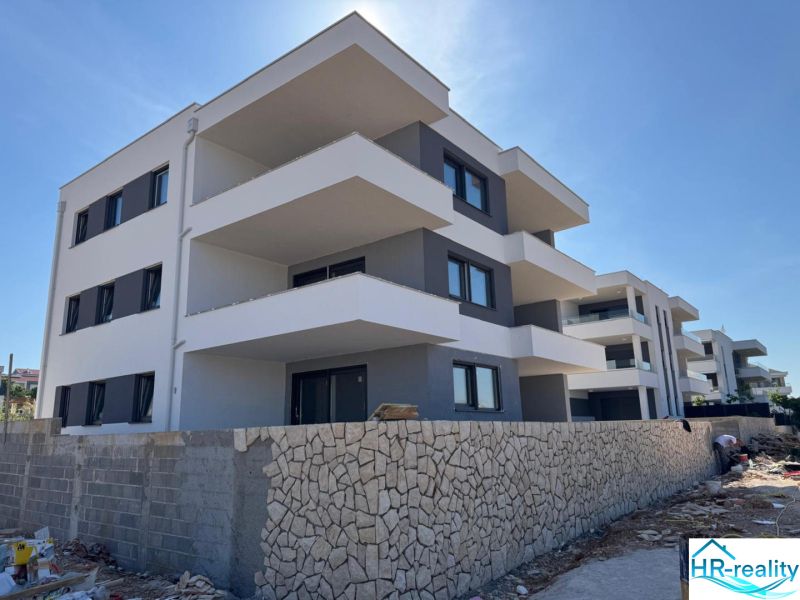 A recreational apartment in Novalja, a three-story building with a stone fence and spacious balconies.