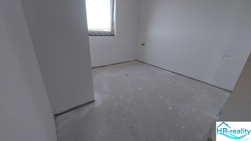 Empty room in a Recreational Apartment with neutral walls and concrete floor.