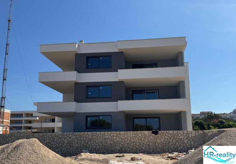 Construction of a recreational apartment in Novalja with a three-story structure and a stone fence.